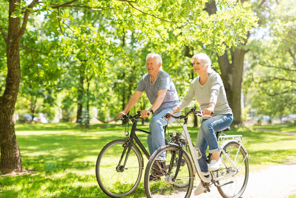 Пожилая пара катается на велосипеде, так как физическая активность способствует укреплению иммунитета.