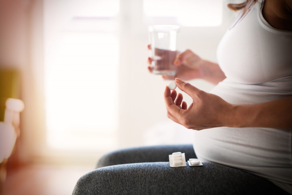 Беременная женщина принимает таблетки от изжоги. 