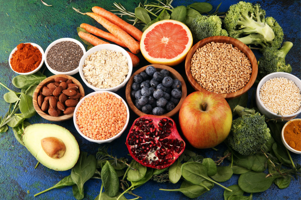 Eine gesunde und vegane Ernährung gestapelt auf Blattspinat: Obst, Gemüse, Samen, Superfoods und Getreide.