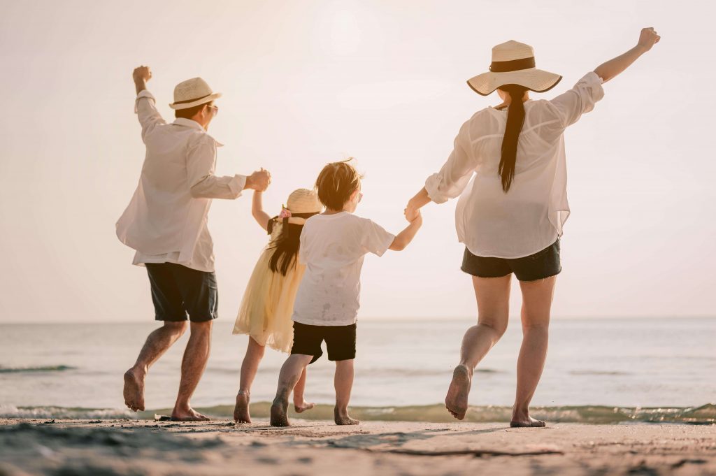 Una famiglia di quattro persone su una spiaggia sabbiosa.
