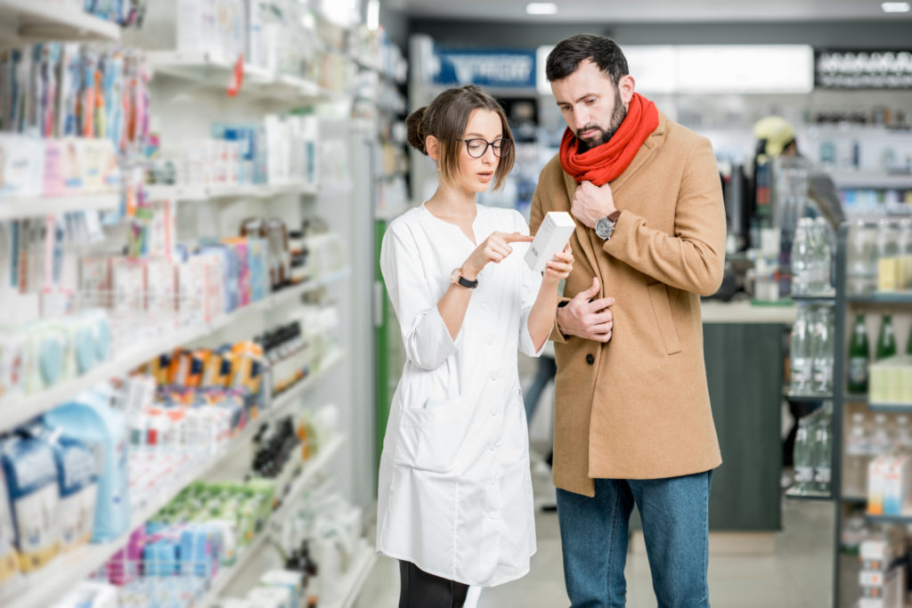 Ustrežljiva farmacevtka svetuje bolnemu moškemu v lekarni.