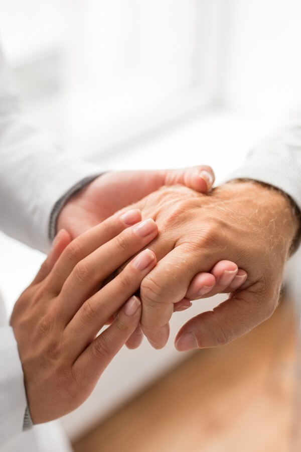 A doctor is compassionately holding the hand of an elderly patient.