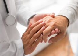A doctor is compassionately holding the hand of an elderly patient.