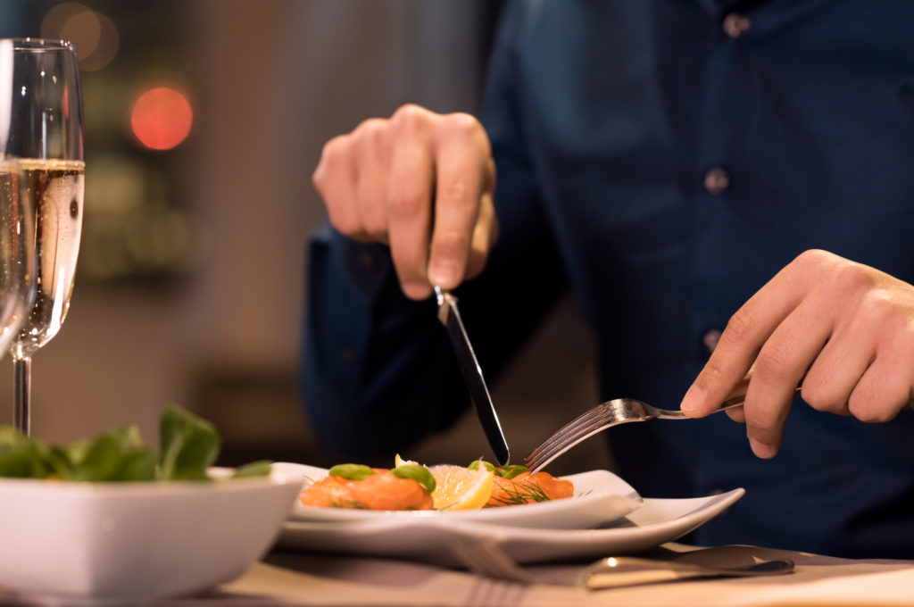 Ein Mann isst ein gesundes Abendessen in einem feinen Restaurant und trinkt Sekt.