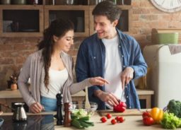 A happy young couple is cooking together in their kitchen.
