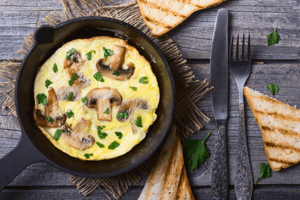 An egg omelet with mushrooms served in a ceramic pan.