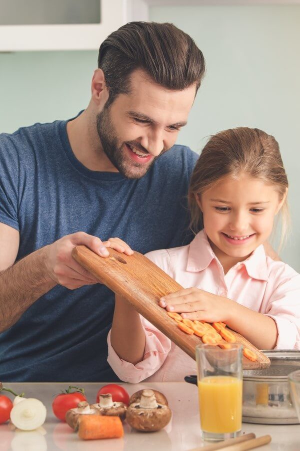 A young father and his daughter are preparing lunch together.
