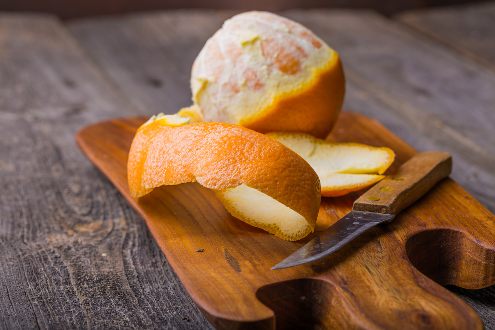 Geschälte Orange auf einem Holzschneidebrett.