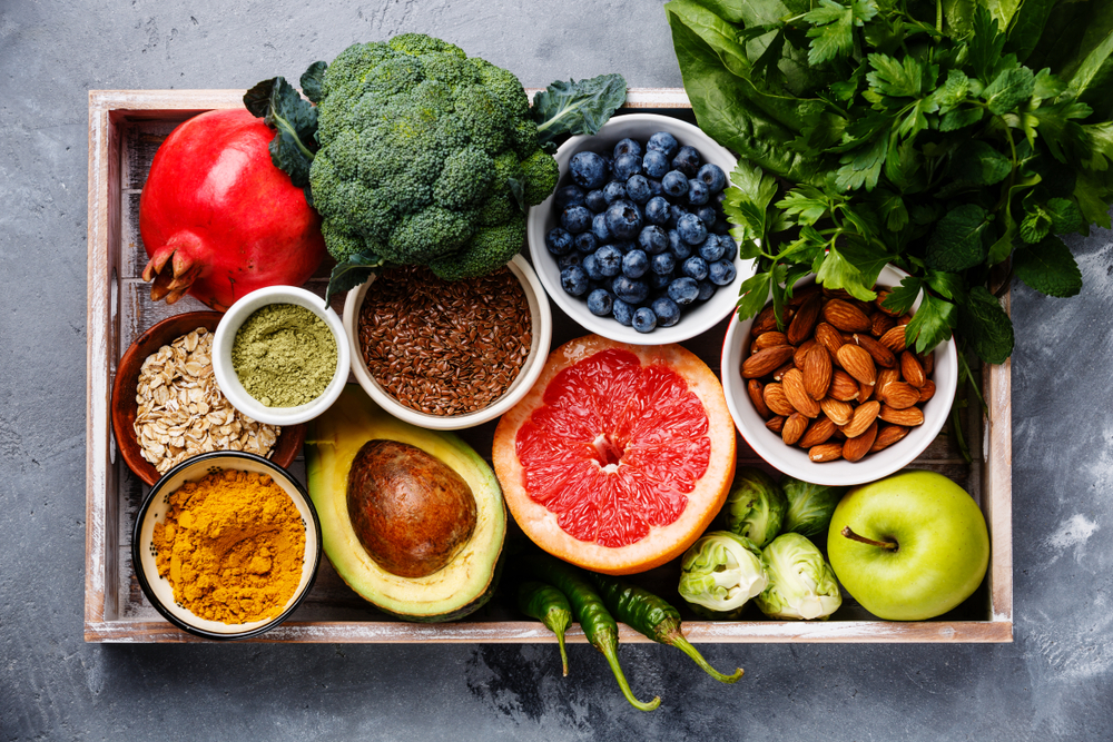 Zdrava in polnovredna živila na lesenem pladnju: sadje, zelenjava, semena, žita, oreščki, začimbe. 