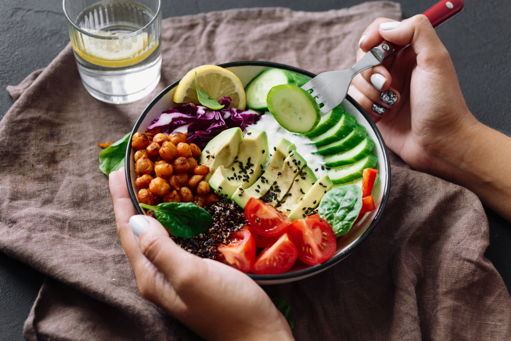 Healthy food. A bowl of salad with cut avocado, tomato, cucumber, roasted chickpeas and seeds.