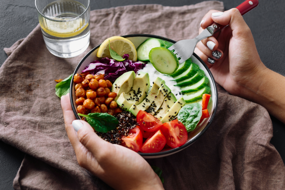 Gesundes Essen. Eine Salatschüssel mit geschnittener Avocado, Tomate, Gurke, gerösteten Kichererbsen und mit der Zugabe von Samen.