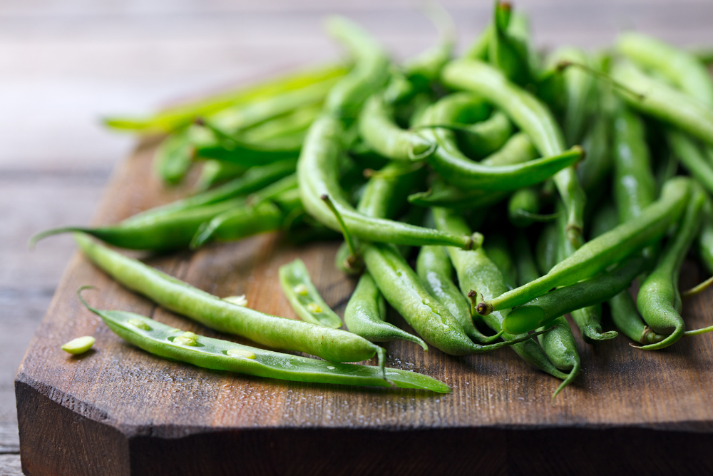 Green beans on a wooden cutting board.