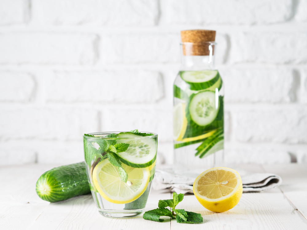 A glass of water with lemon, cucumber and mint.