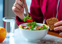 An employee is having lunch at his workplace – a salad and crackers.