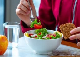 An employee is having lunch at his workplace – a salad and crackers.