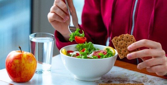 An employee is having lunch at his workplace – a salad and crackers.