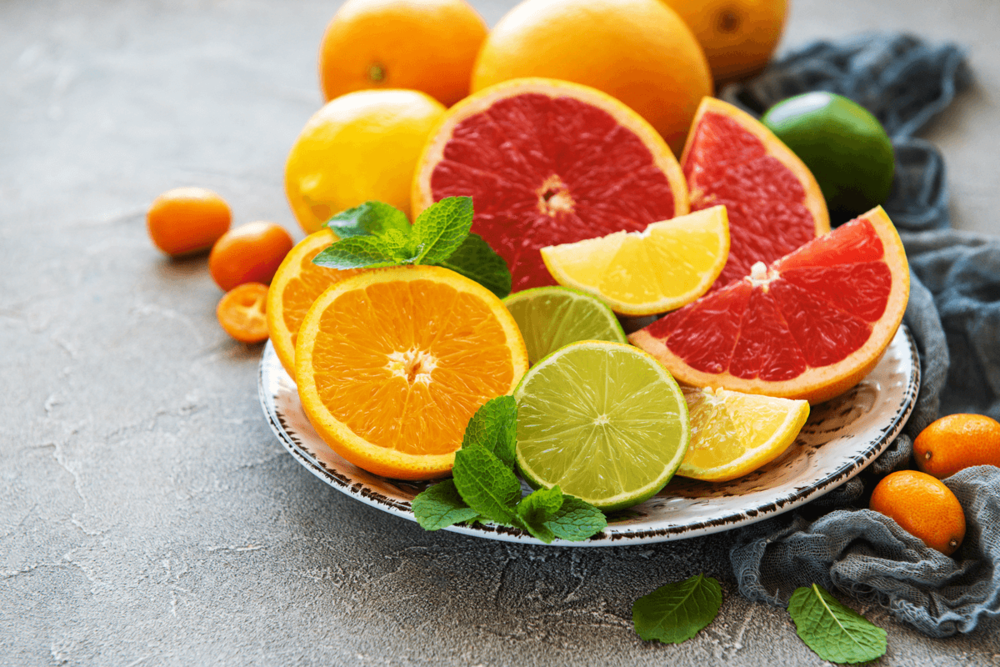 Cut citrus fruit on a plate: oranges, limes, lemons, red oranges.