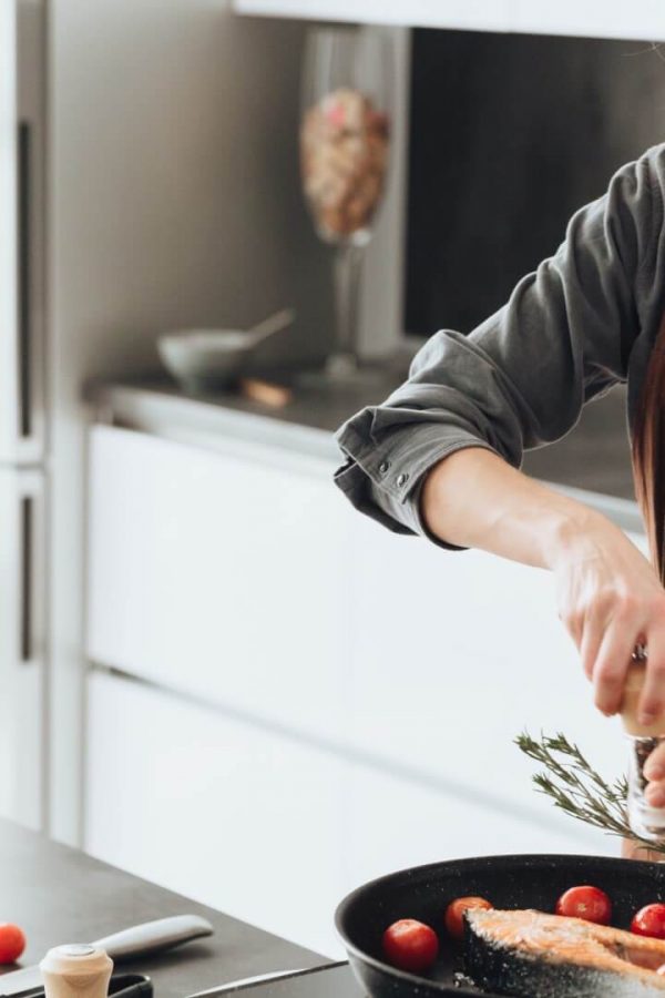 Eine junge Frau bereitet Lachs zum Mittagessen zu, weil er viele Omega-3-Fettsäuren enthält.