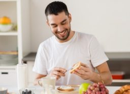 Der Mann lacht beim Zubereiten eines gesunden Frühstücks.