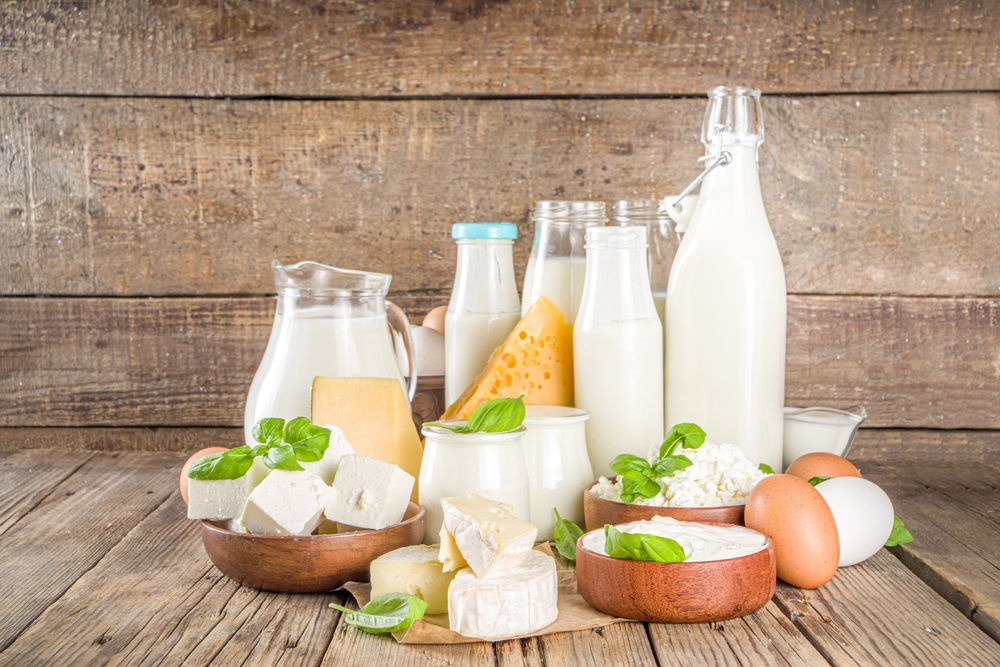 Diversi tipi di latticini freschi: formaggio fresco, formaggio, latte, panna e yogurt, in dei contenitori ed in bottiglie di vetro.