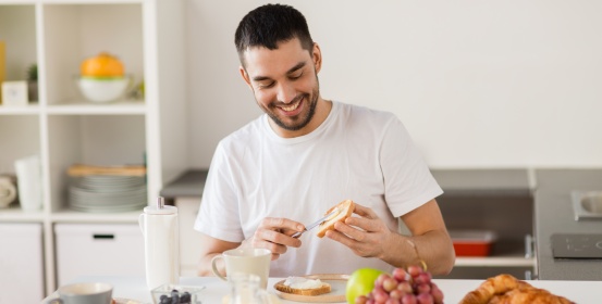 Moški se smeji ob pripravi zdravega zajtrka.