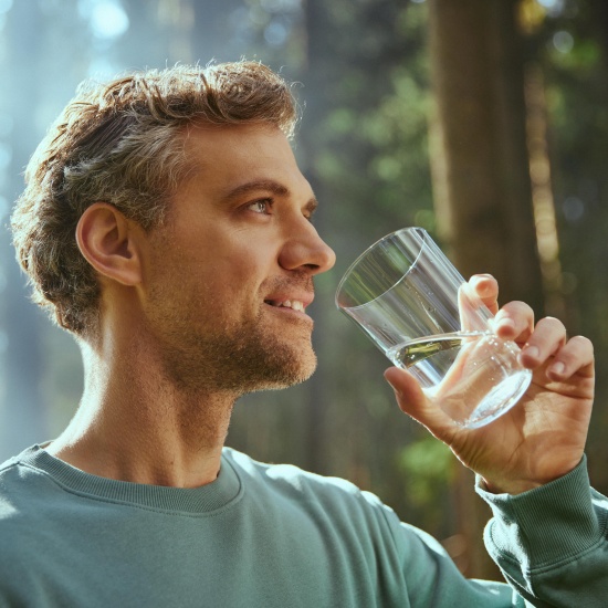 Der Mann trinkt Wasser aus einem Glas.