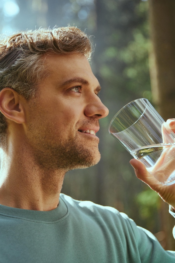 Der Mann trinkt Wasser aus einem Glas.