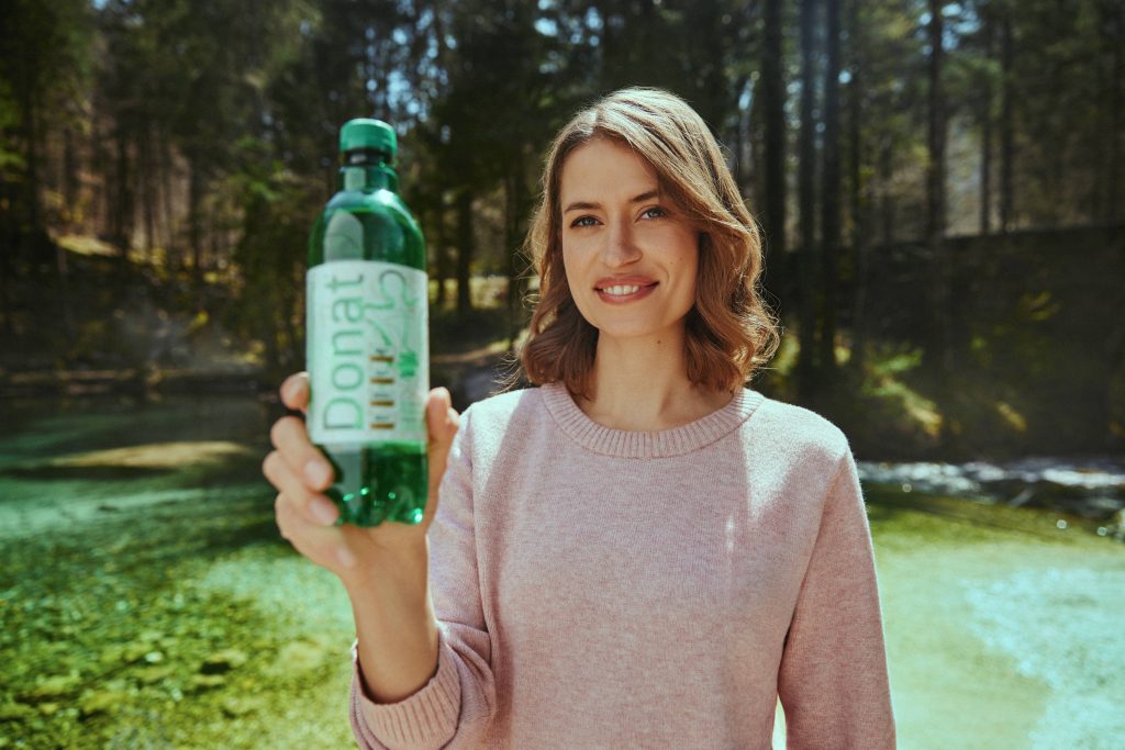 Una donna tiene in mano una bottiglia di Donat Mg.
