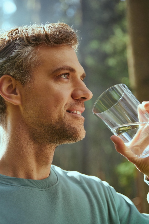 The man drinks water from a glass.