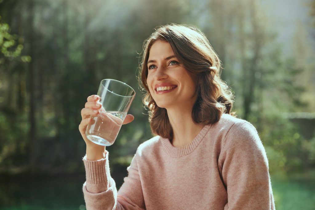 A woman holds a glass of water in her hands.