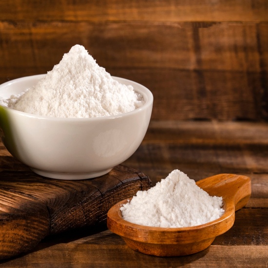 Baking soda on a wooden spoon and in a ceramic cup.