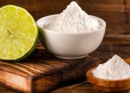 Baking soda on a wooden spoon and in a ceramic cup.