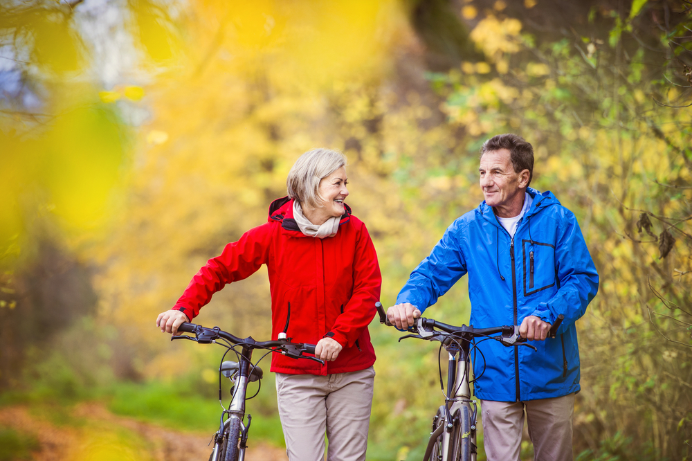 Aktivni starejši na sprehodu s kolesom v jesenski naravi. Imajo romantičen čas na prostem.