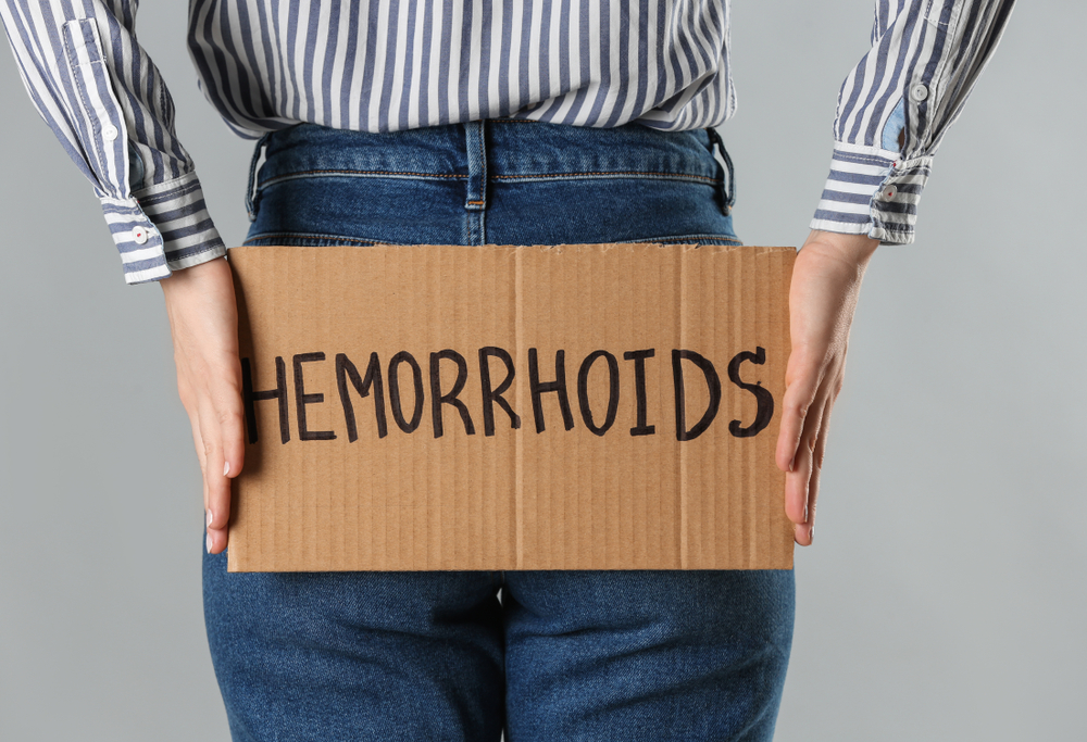 A woman holds a poster with the inscription in English - hemorrhoids