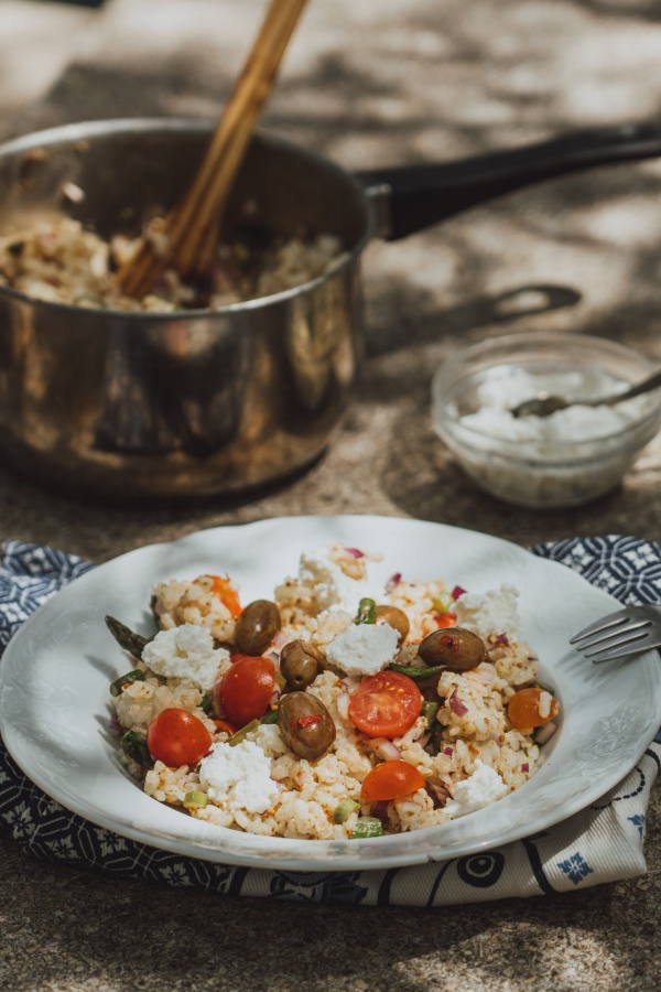 Salata od riže sa šparogama na keramičkom tanjuru.