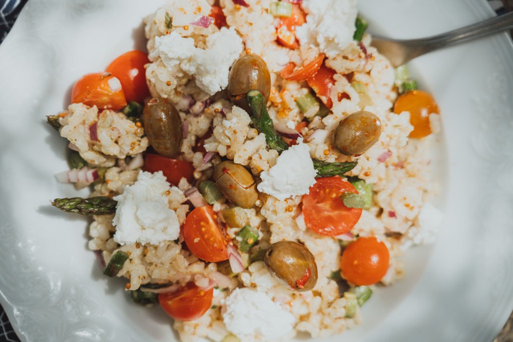 Salata od riže sa šparogama na keramičkom tanjuru.