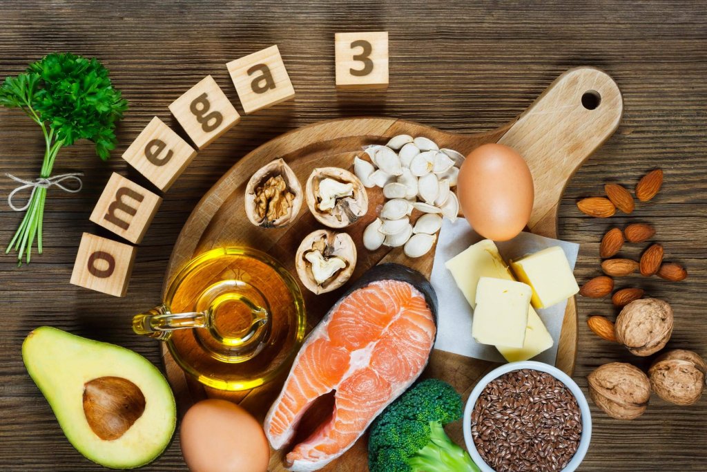 Different types of Omega-3 fatty acids on the table: avocado, almonds, salmon, eggs, nuts.