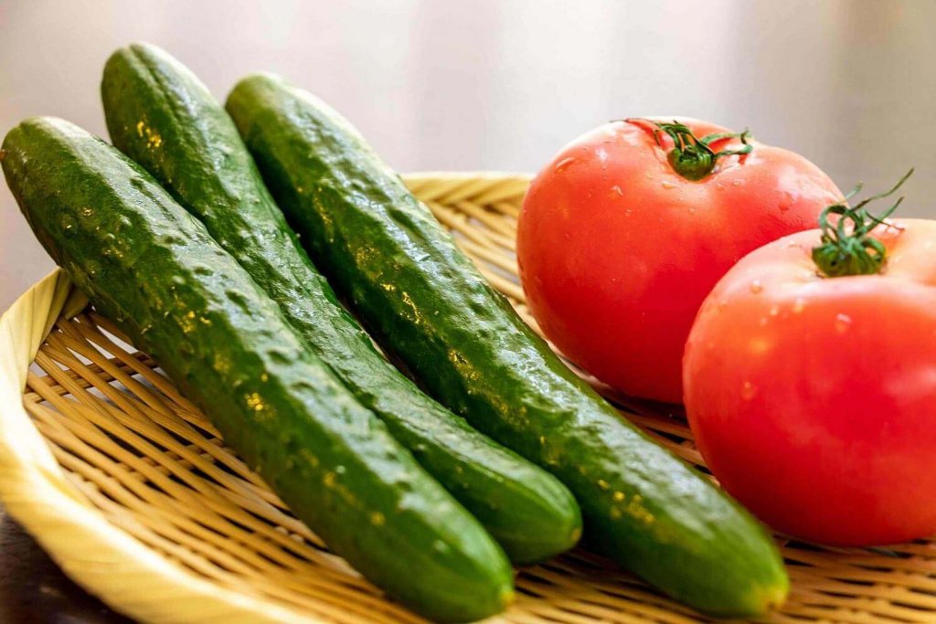 Tomaten und Gurken auf einem hölzernen Hintergrund.