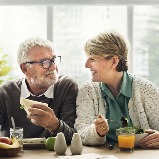 An elderly couple at the table has a healthy and tasty dinner.