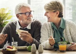 An elderly couple at the table has a healthy and tasty dinner.