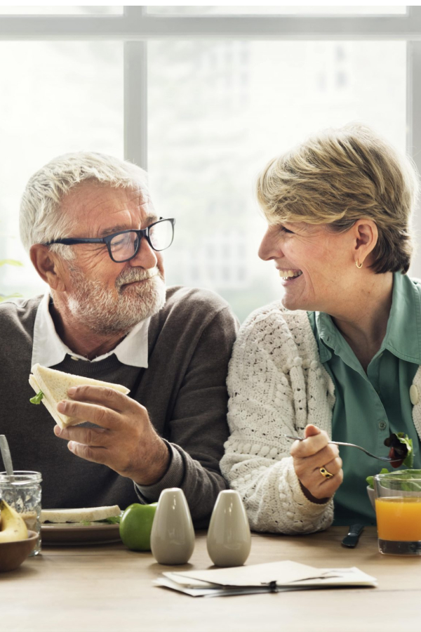 An elderly couple at the table has a healthy and tasty dinner.