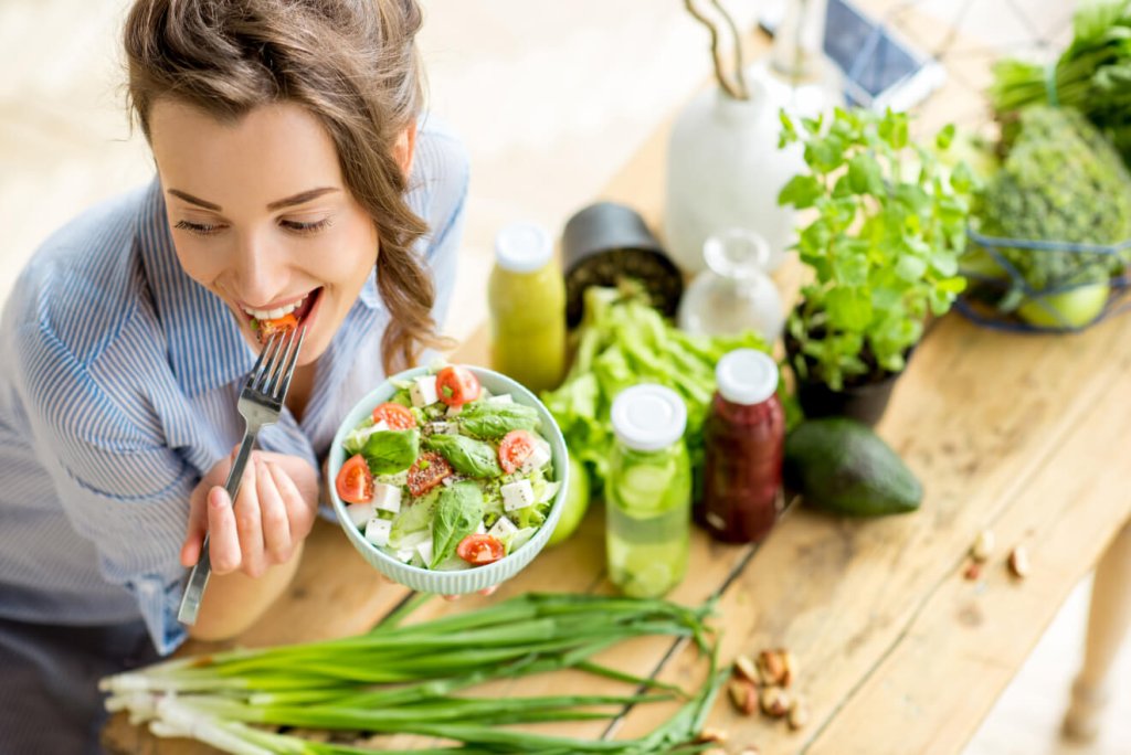 Una giovane donna sta sgranocchiando una sana insalata.