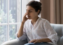 ženska z bolečino na kavču v sodobnem domu